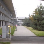 Fußgängerweg mit Schranke in der Nähe der Allianz Arena, der zu einer Hängebrücke im städtischen Umfeld führt. Fritten, Fussball & Bier - www.soccer-warriors.de