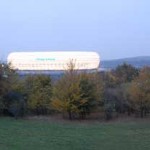 Ein großes weißes Gebäude, bekannt als Allianz Arena, mitten auf einem Feld. Fritten, Fussball & Bier - www.soccer-warriors.de