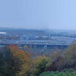 Dämmerung über einem Industriegebiet mit Autobahn, Herbstlaub und Blick auf die Allianz Arena, die sich auf den Bundesligasamstag vorbereitet. Fritten, Fussball & Bier - www.soccer-warriors.de